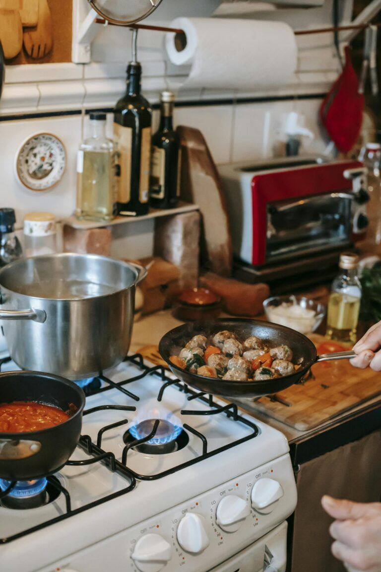 A cozy kitchen setting with meatballs frying on the stove and sauce simmering nearby.