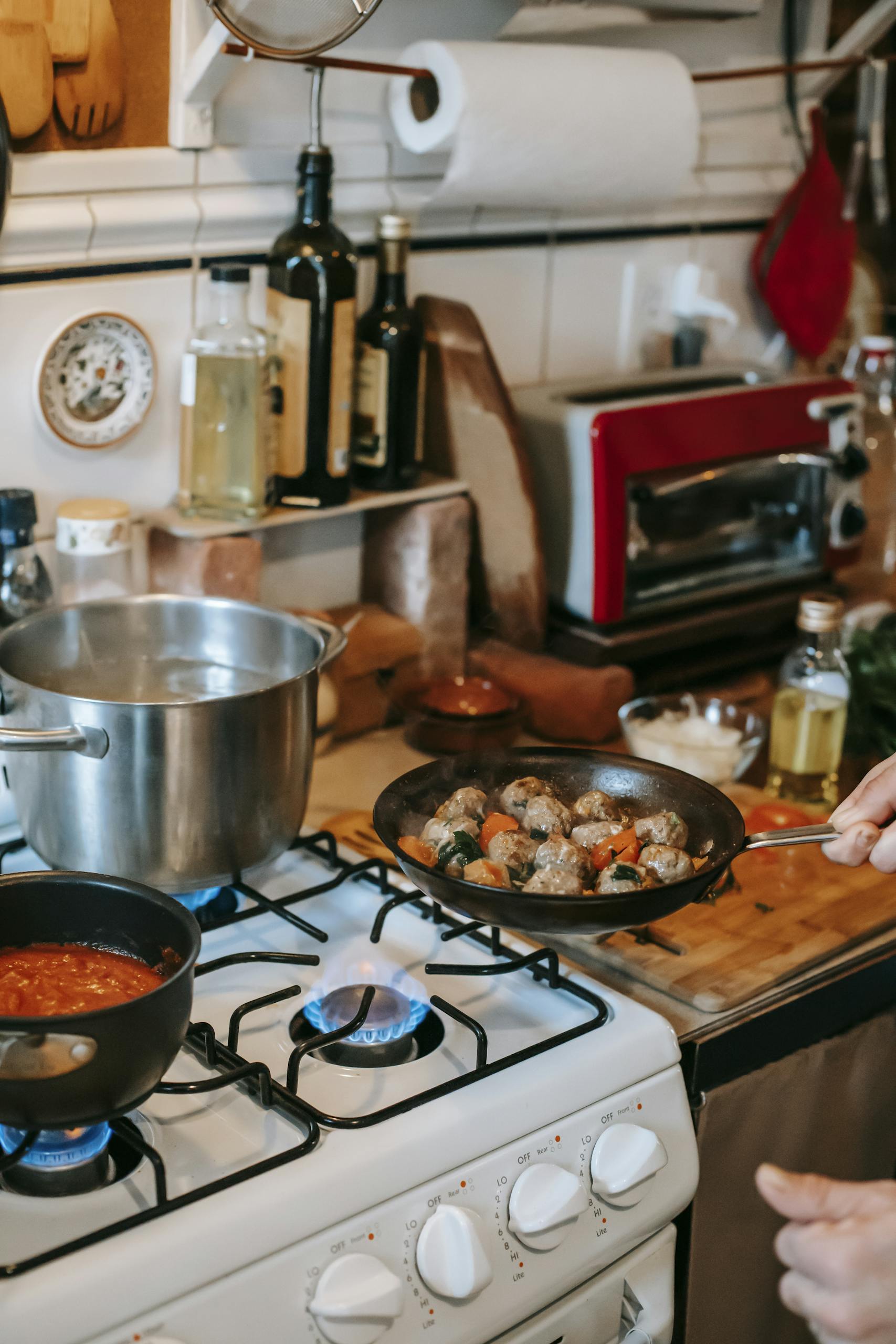 A cozy kitchen setting with meatballs frying on the stove and sauce simmering nearby.